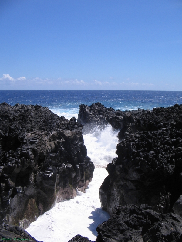 La mer entre dans une faille de lave noire au gouffre de l’Étang-Salé.