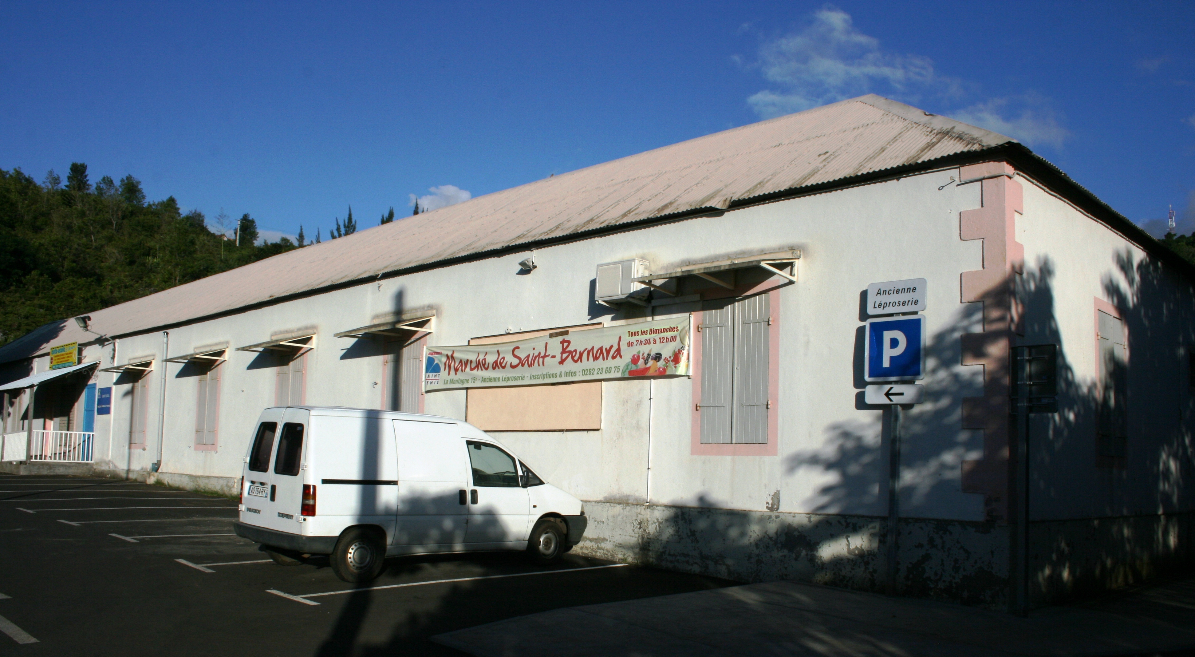 Aile blanche de l’ancienne léproserie de Saint-Bernard, avec un panneau Ancienne Léproserie et une banderole de marché, en 2011.